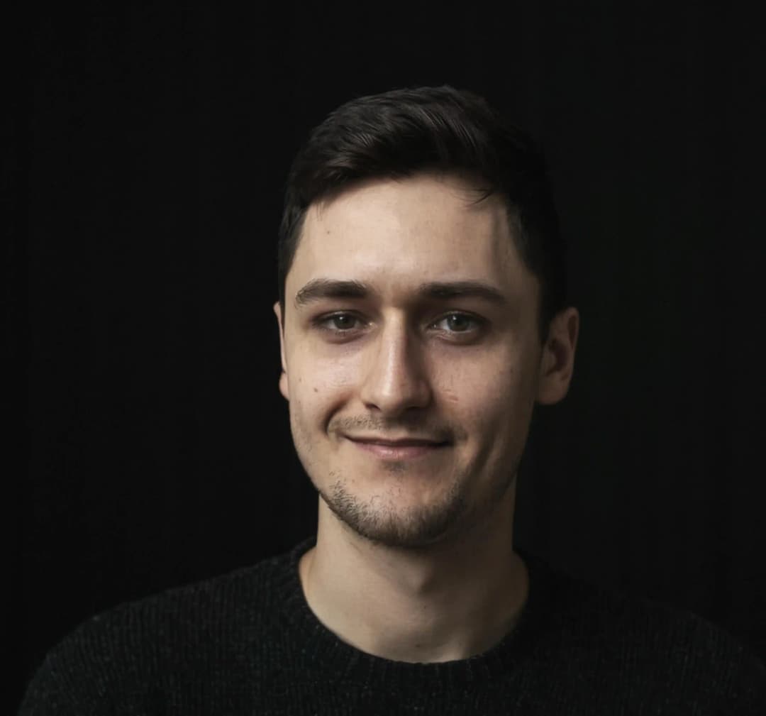 Photo showing a portrait of Adam Noszczyński in a black sweater on a black background