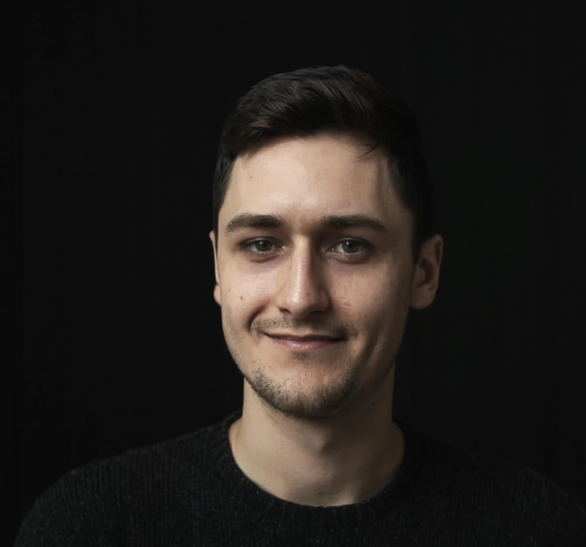 Zdjęcie przedstawia portret Adama Noszczyńskiego w czarnym swetrze i na czarnym tle