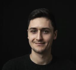 Zdjęcie przedstawia portret Adama Noszczyńskiego w czarnym swetrze i na czarnym tle